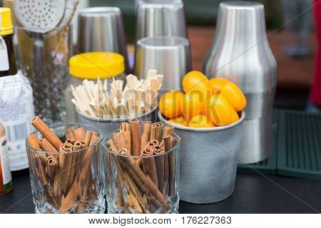 Making mulled wine for sale at country fair. Glintwine accesories, stirring wooden sticks, spices and citrus, cinnamon sticks and kumquat in metal bowls closeup.