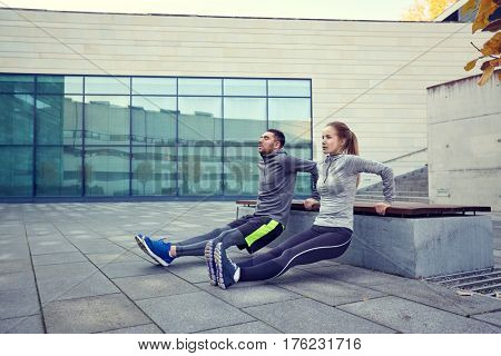 fitness, sport, training, people and lifestyle concept - couple doing triceps dip exercise on bench outdoors