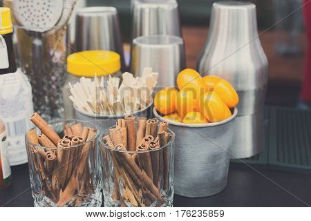 Making mulled wine for sale at country fair. Glintwine accesories, stirring wooden sticks, spices and citrus, cinnamon sticks and kumquat in metal bowls closeup.