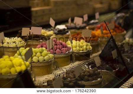 Large selection of chocolates on counter of market store in dark room. Wide assortment of candy selective focus