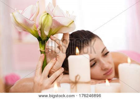 Beutiful woman relaxing after massage in pleasing illuminated room with plants and aroma candles