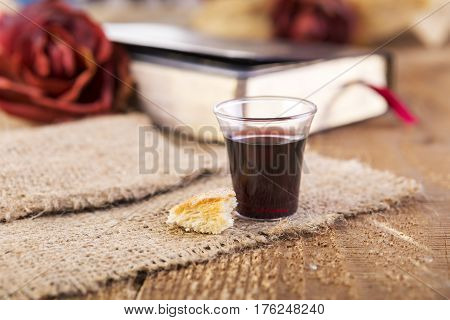 Taking Communion. Cup of glass with red wine bread and Holy Bible on wooden table close-up. Focus on bread.