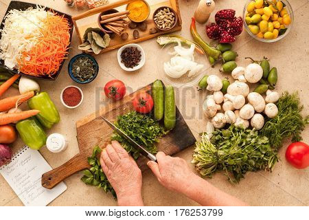 Cooking fresh vegetarian lunch from tomatoes cucumber greenery and onion. Sliced vegetables prepared for making meal.