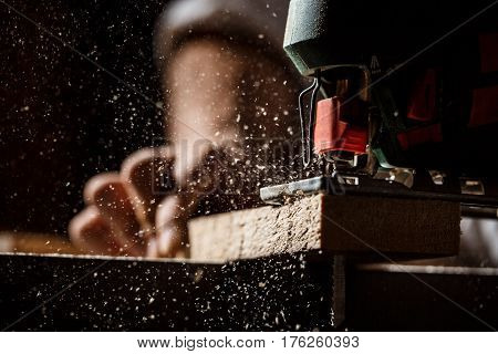 Close up photo of cutting wood with fretsaw over dark background. Copy space.