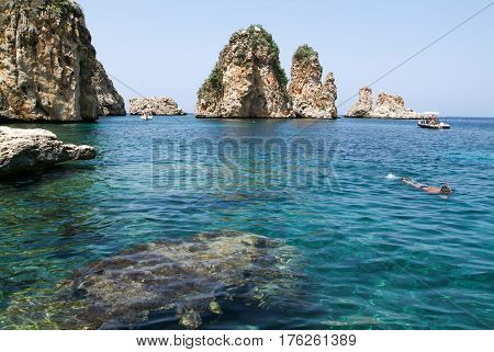 People Snorkeling In Front Of Faraglioni At Scopello On Sicily