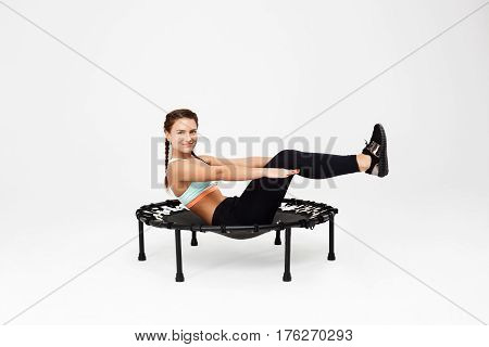 Nice woman with bunches working out abs training on rebounder looking straight with kind smile