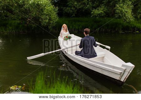 The groom and bride are floating on the river on the white boat