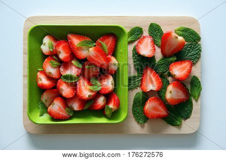 Fresh strawberry with leaves of mint on the white background.