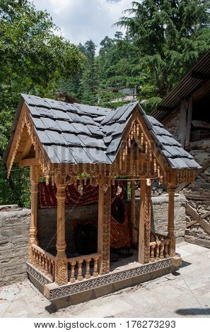 MANALI, INDIA. A small Shiva Temple decorated with wood-carved a swastika and iron tridents.  Naggar, district of Kullu in Himachal Pradesh, India.