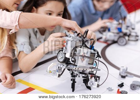 Streamlined robot. Modern futuristic electronic robot standing in front of the children on the table and performing functions while demonstrating tech progress