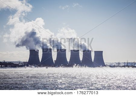 Cooling towers of a Nuclear Power Plant or NPP with thick smoke on blue sky background in sunny day. Copy space for text