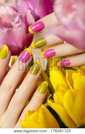 Yellow green French manicure with pink nail Polish and tulips closeup.Nail art.