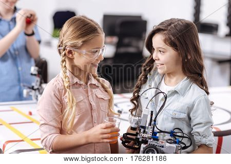 Taking part in the science experiment. Inventive clever capable pupils standing at school and testing cyber devices while having science lesson