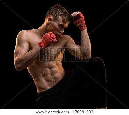 Muscular man during boxing training on black background