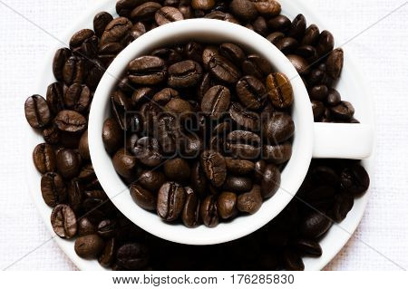 coarse grains of coffee in a white cup and around it