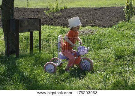 Cute girl playing outdoors with a bike and an old bucket helmet