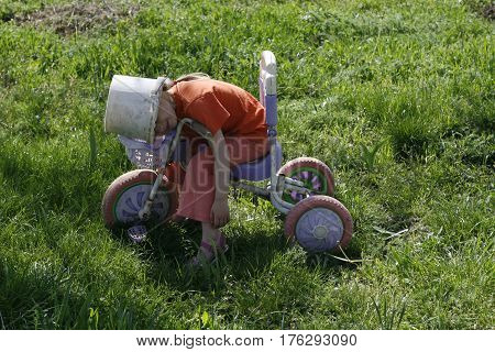 Cute girl playing outdoors with a bike and an old bucket helmet