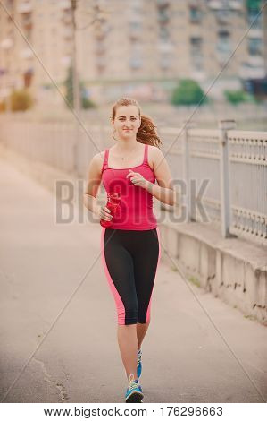 young athletic girl perfoms exercises in the gym running sports and exercieses in the park
