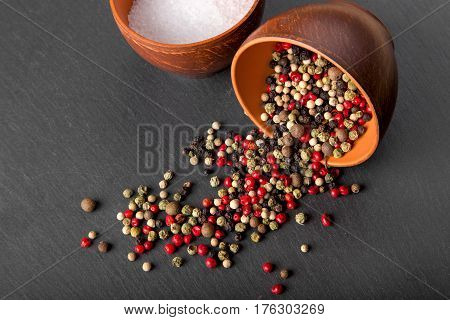 salt and pepper in a clay bowl on a slate board pepper is scattered