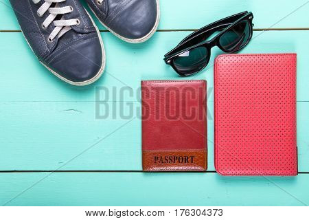 set for traveling passport e-book sneakers sunglasses. on a wooden turquoise surface a top view