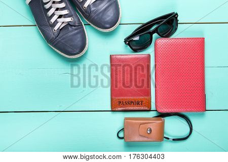 set for traveling passport e-book sneakers sunglasses camera. on a wooden turquoise surface a top view