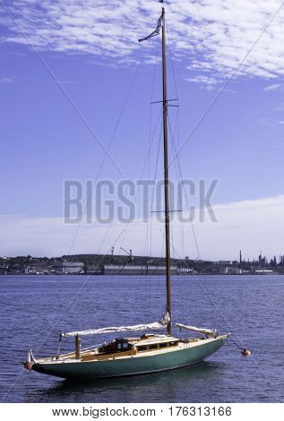 Halifax, Nova Scotia, September 23, 2015 -- Vertical view of a docked sailboat in the Halifax Harbor with the industrial buildings of Dartmouth in the background on a bright sunny day in Halifax, Nova Scotia