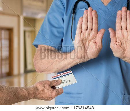Senior caucasian doctor in scrubs in hospital refusing to treat a patient with a Medicare card