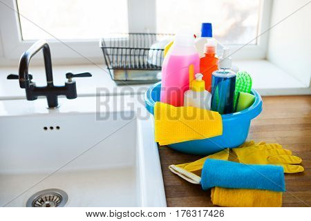 Basket With Cleaning Items On Blurry Background White Citchen. Cleaning Concept.