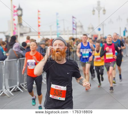 BRIGHTON GREAT BRITAIN - FEB 26 2017: Man with red beard and competitors running in the Vitality Brighton half marathon competition. February 26 2017 in Brighton Great Britain