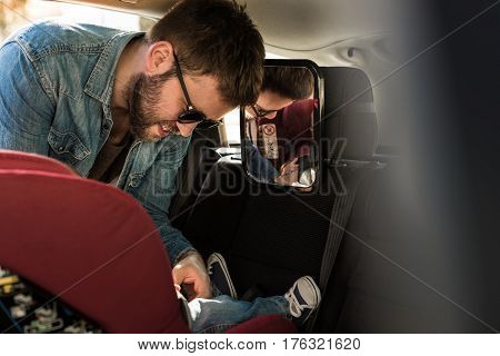 Father Fasten His Baby In Car Seat