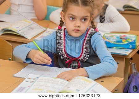 First-grader At A Lesson Of Mathematics Solves Examples And Look At The Board