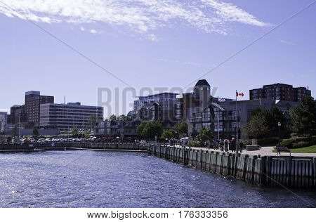 Wide view of the commerce and people milling about on the boardwalk at Halifax Harbor on a bright sunny day in September in Halifax, Nova Scotia
