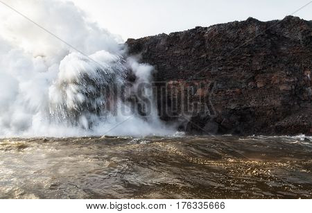 Large explosions occur as hot lava flows into cold sea water completely hiding the large fire hose molten lava flow.