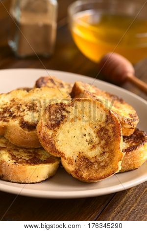 French toast made of baguette honey and cinnamon powder in the back photographed with natural light (Selective Focus Focus on the upper part of the standing toast)