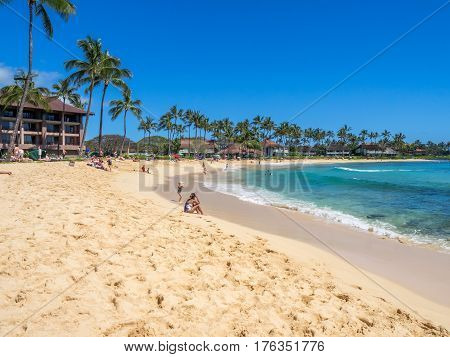 KAUAI, USA - MAR 5: Tourists and locals enjoy Poipu Beach on March 5, 2017 on Kauai, Hawaii. Poipu Beach is one of the most popular tourist areas on the island of Kauai and has many excellent hotels.