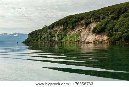Beautiful coast of the Kurile Lake is reflected in the water.