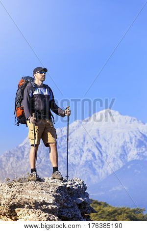 A man with a backpack hiking in the mountains on a sunny day.