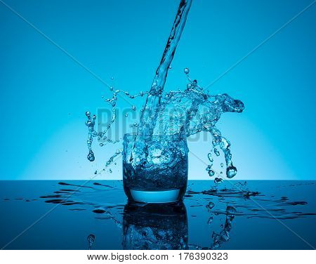 Сreative splashing water in the glass on blue background.