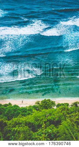 Man walking along of Nunggalan Beach. Big waves rolling on. Uluwatu, Bali, Indonesia.