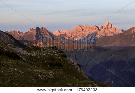 Great clear view from high mountain over other peaks. Evening or morning sunlight illuminates the mountains. Alps, Bavaria, Tirol, Allgau.