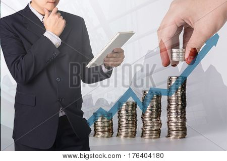 Double exposure Confident Asian businessman reading notebook or document file and thinking with financial growth graph chart on blurred stacks of coins with calculator background Money Financial Business Growth and saving money concept.