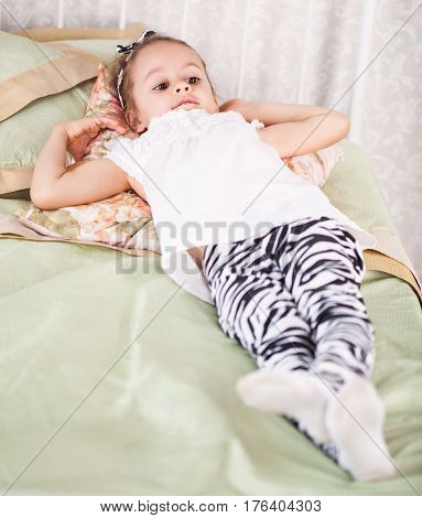 Little girl is lying on the bed