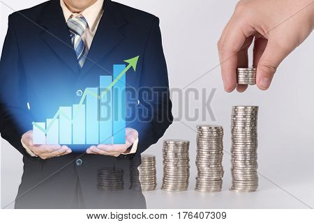 Double Exposure Of Growth Graph On Businessman Hand With Blurred Hand Put Coin In Stacks Of Coins Ba