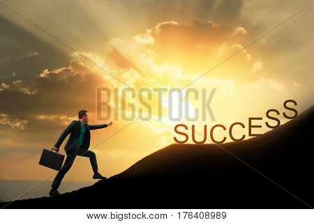 Silhouette of successful businessman with briefcase walking to top of mountain with powerful of sunlight sky background. Young worker reaching goal success and achievement in his life. Copy space.