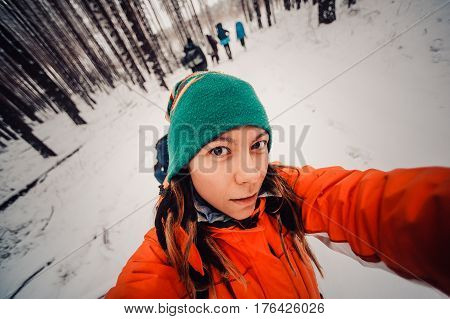 Winter sport activity. Woman hiker hiking with backpack and snowshoes snowshoeing on snow trail forest in Russia at sunset. Beautiful landscape with coniferous trees and white snow. selfie