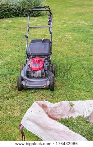 lawn mower and a bag of cut grass on the green lawn