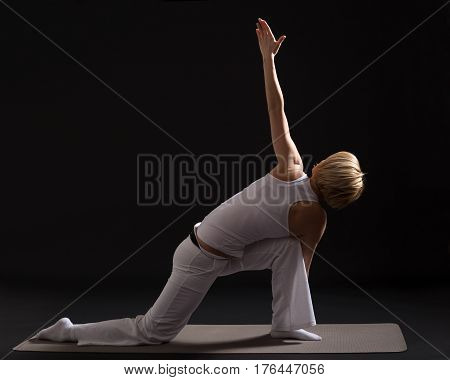 Woman exercising yoga indoor on black background,Bikram triangle   /Trikonasana