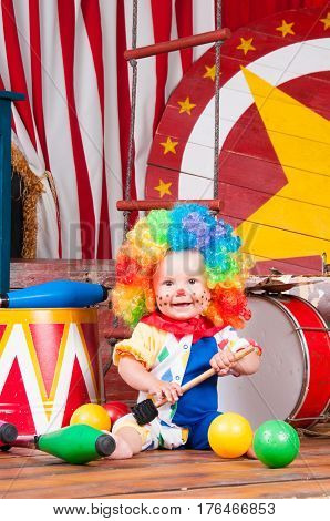 Little baby clown with red nose multi-colored wig in with balls.