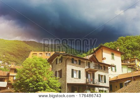 Beautiful colorful cityscape of italian Varenna city with building green mountain trees and dramatic cloudy sky before the rain