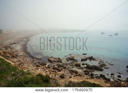 Rocky coastline of Tabarca Island. Crystal-clear turquoise water. Foggy weather in march. Province of Alicante. Spain